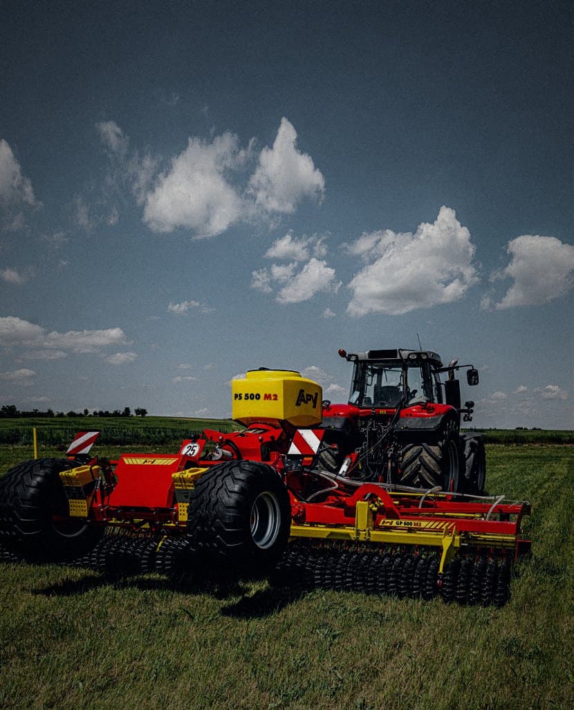 Sembradora APV PS 500 M2 sobre rodillo de pradera y tractor rojo en pastizal abierto