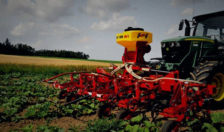 Sembradora APV PS 120 M1 montada sobre cultivador y tractor John Deere, trabajando junto a campo de trigo