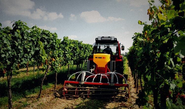 Sembradora APV PS 200 M1 montada sobre tractor rojo, sembrando cobertera entre hileras de viñedo