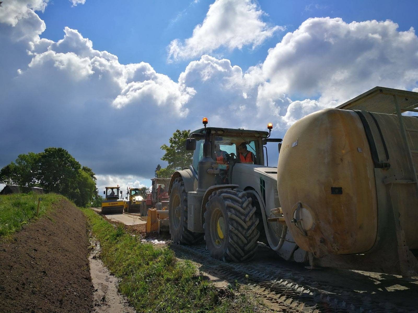Tractor con cisterna de agua trabajando junto a la cuneta de un camino