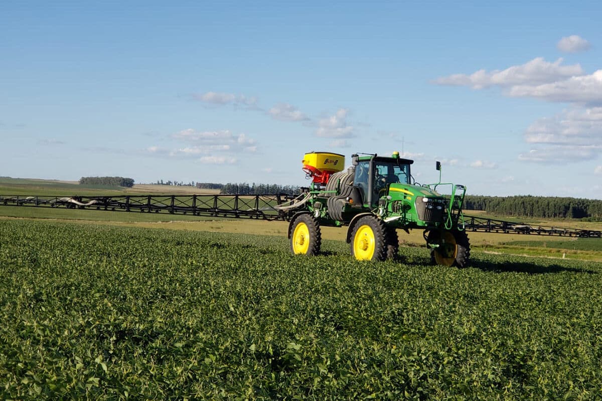 Tolva APV montada en un pulverizador autopropulsado verde, avanzando sobre un cultivo en pie