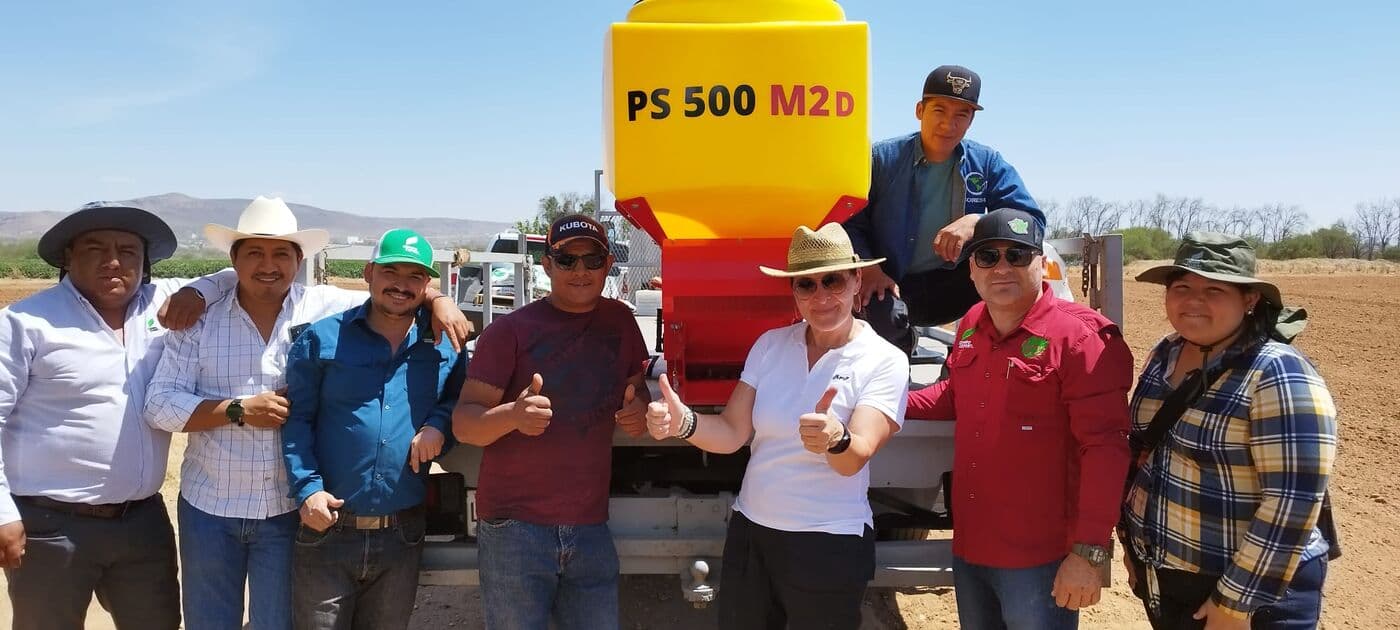 Grupo de productores con sombrero junto a una sembradora APV PS 500 M2 D recién entregada, en campo abierto