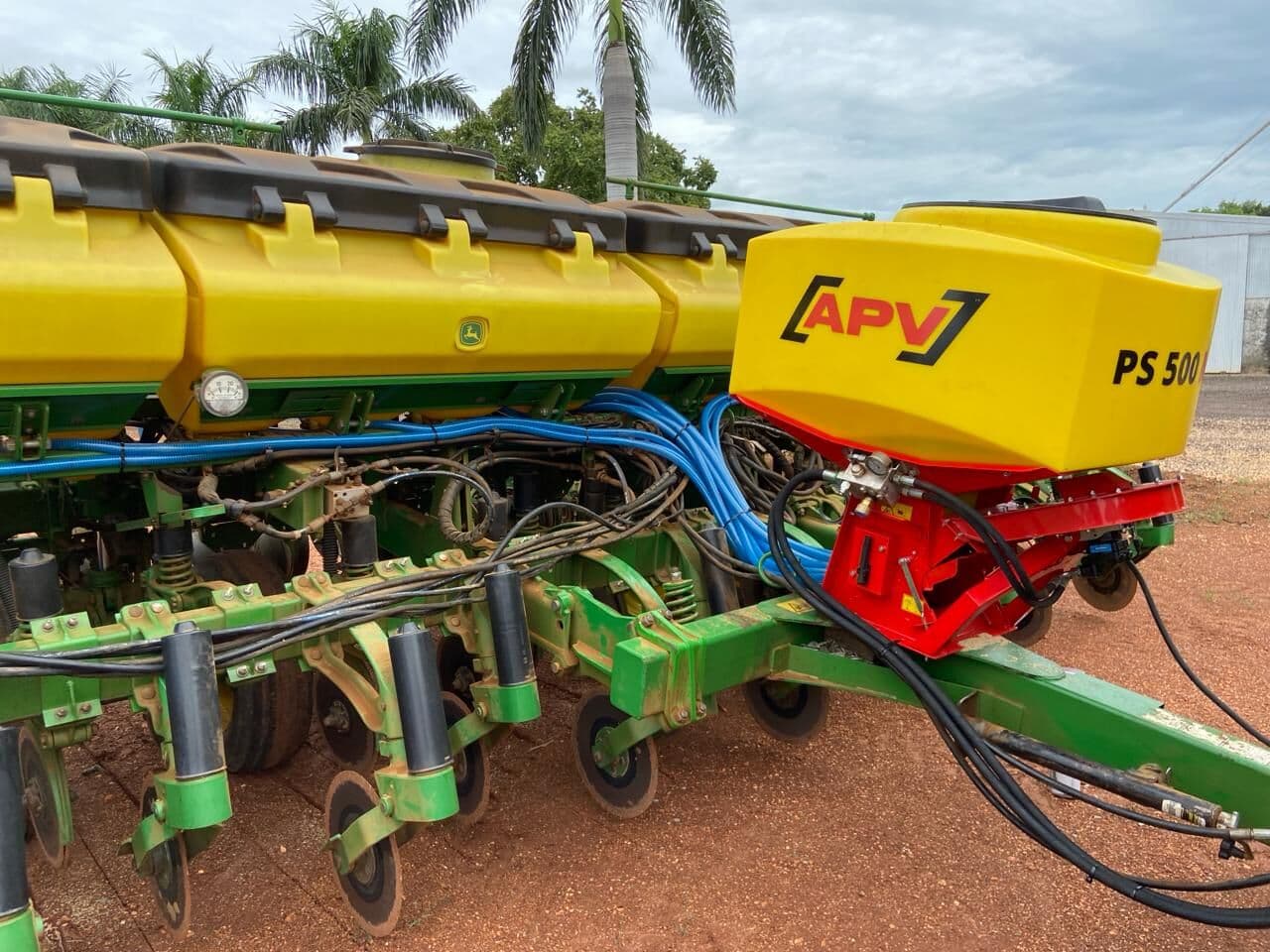 Tolva APV PS 500 alimentando una sembradora de precisión verde, con palmeras al fondo