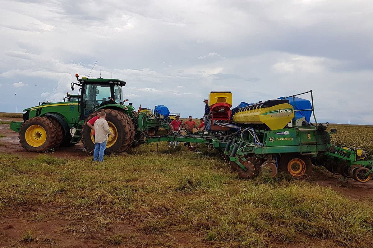 Sembradora neumática de siembra directa con tolva APV, tractor verde y operadores en un campo con rastrojo