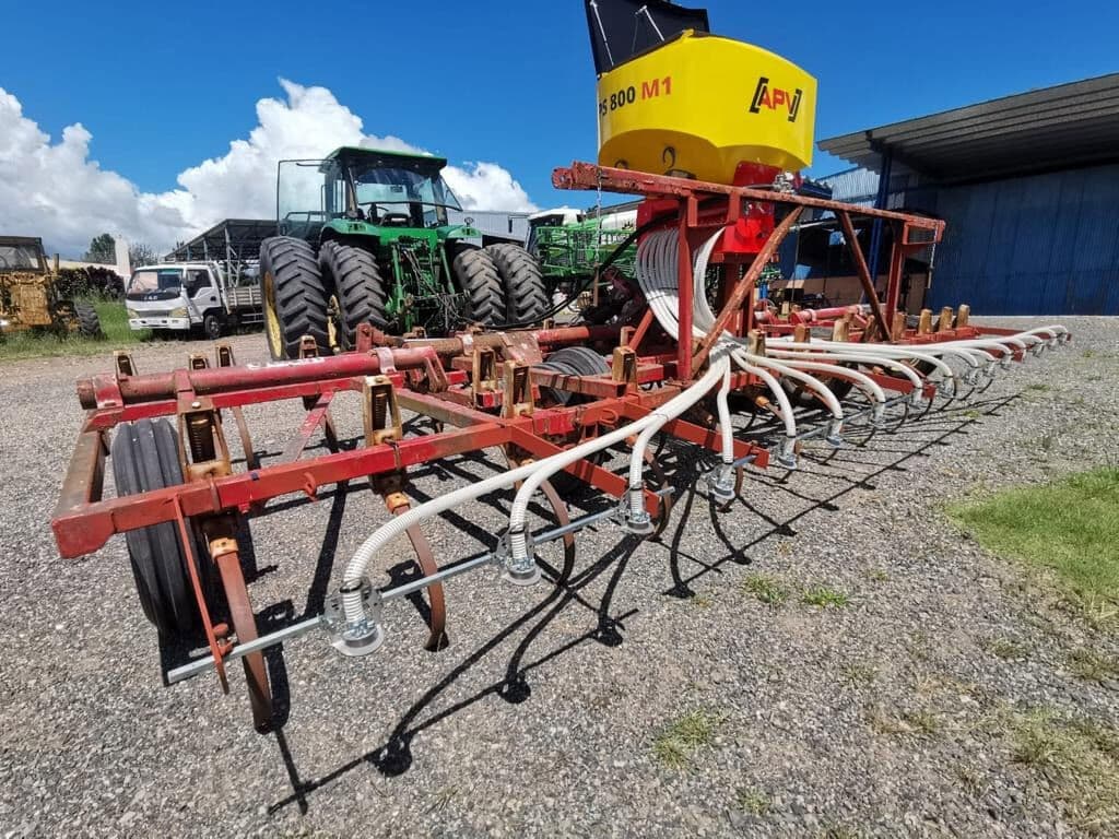 Tolva APV con mangueras blancas sobre un cultivador de campo rojo