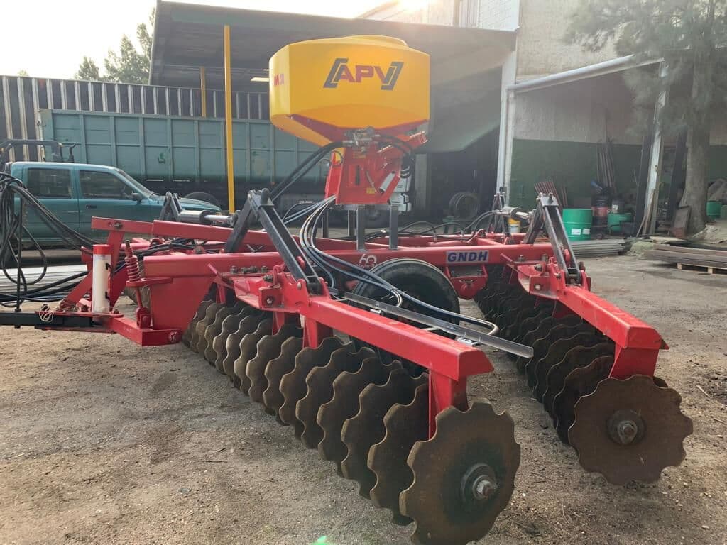Tolva APV con mangueras sobre una rastra de discos roja