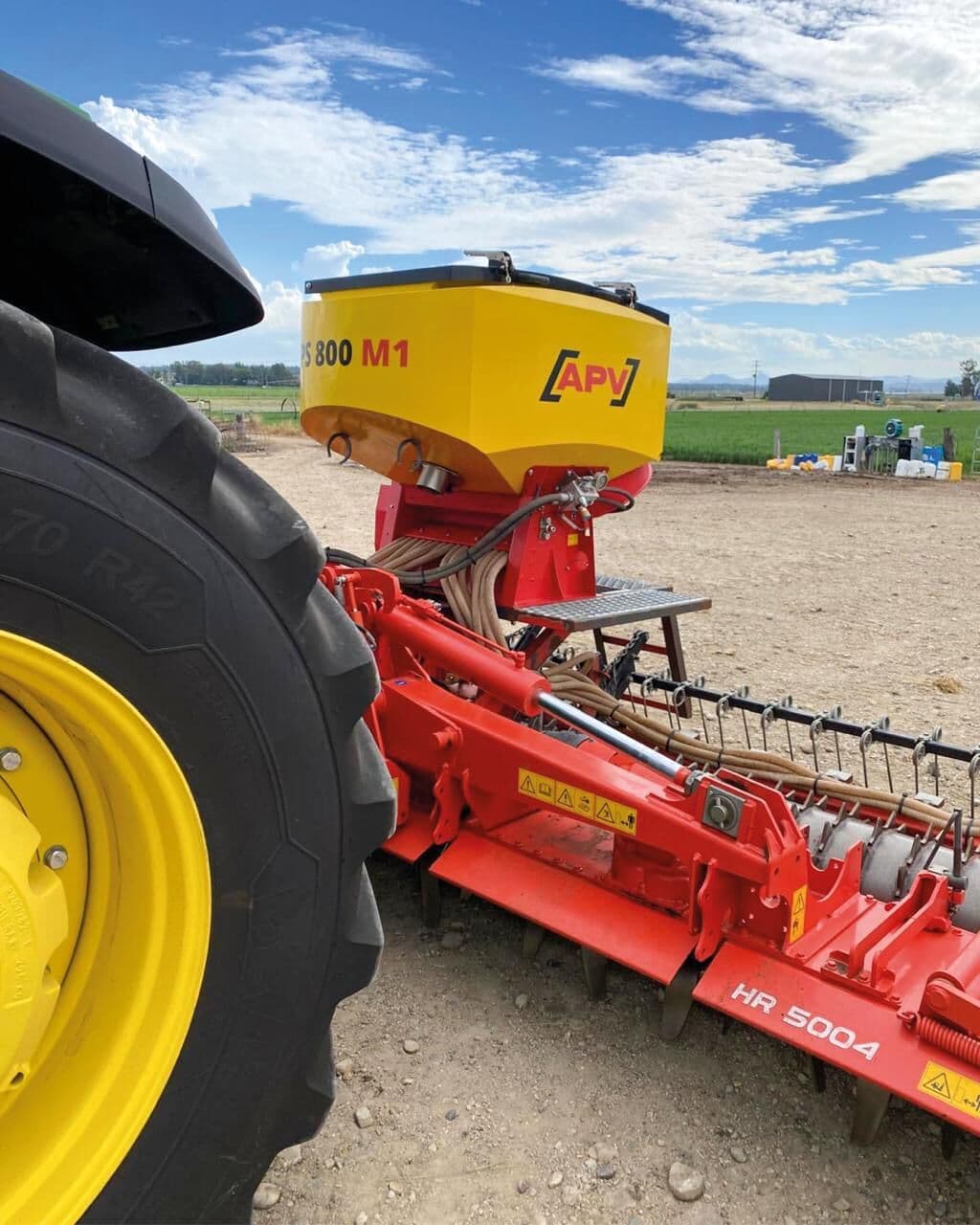 Tolva APV sobre una rastra rotativa roja con tractor, en campo