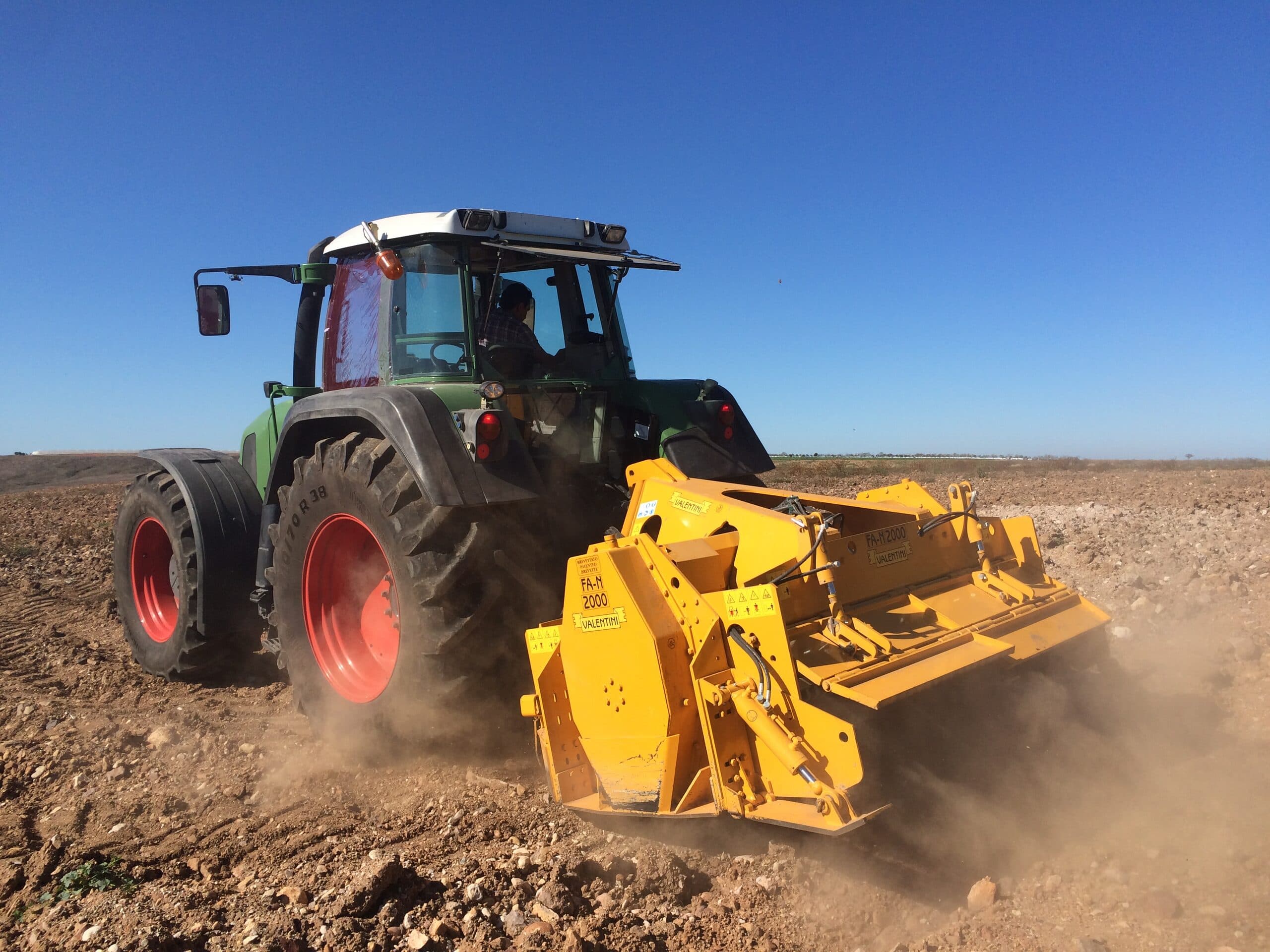 Tractor Fendt con trituradora Valentini ATTILA FA-M 2000 triturando piedra bajo cielo azul
