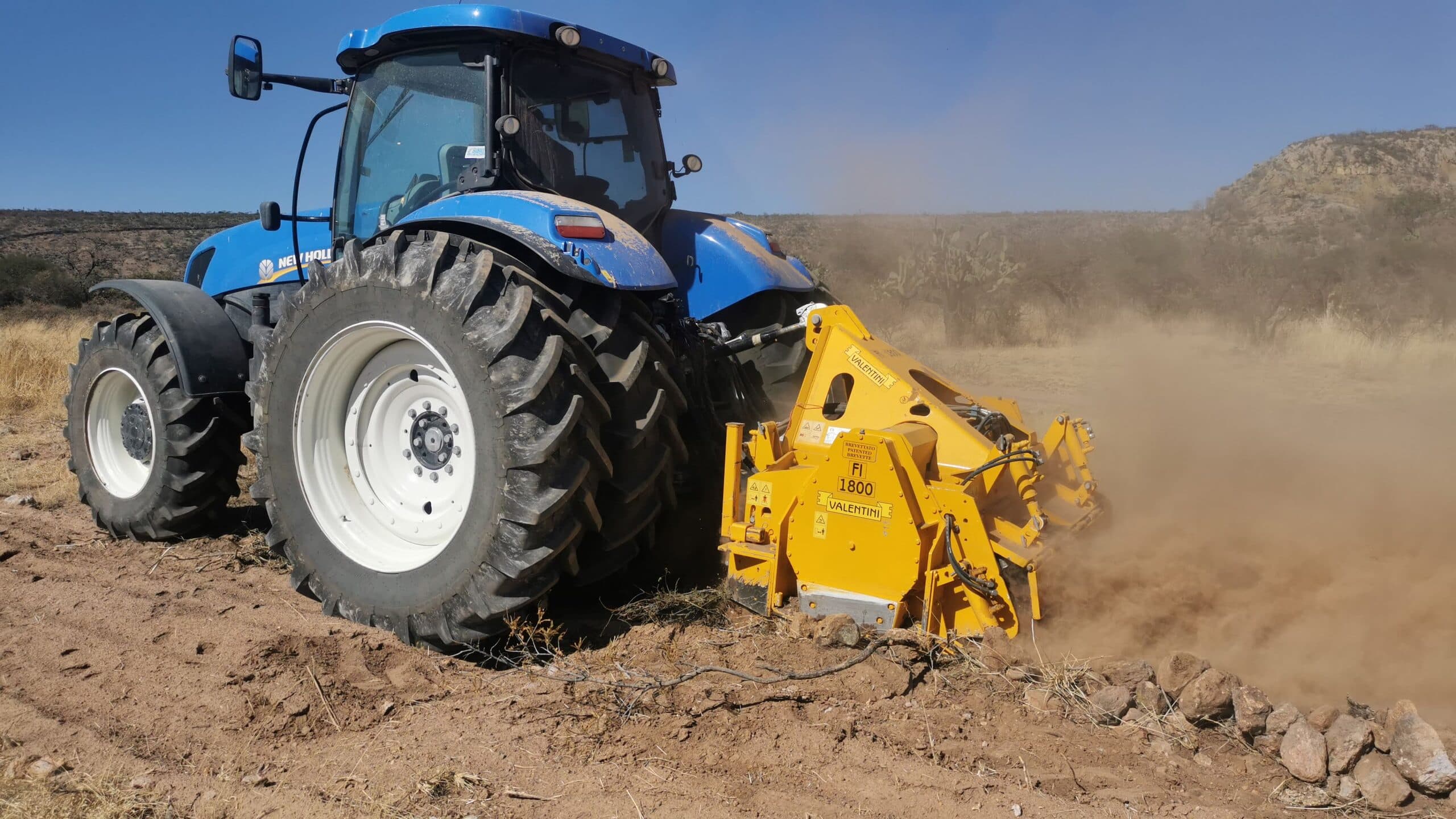 Tractor New Holland con trituradora Valentini IVAN FI 1800 triturando piedra entre una nube de polvo